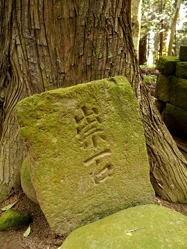 杉の木の下に置かれる「祟石」