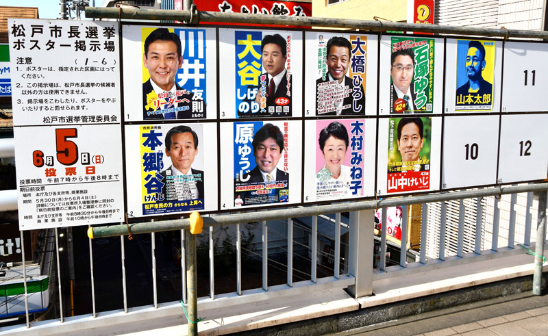 過去最多の立候補者９人のポスターが並ぶ掲示板＝ＪＲ松戸駅前