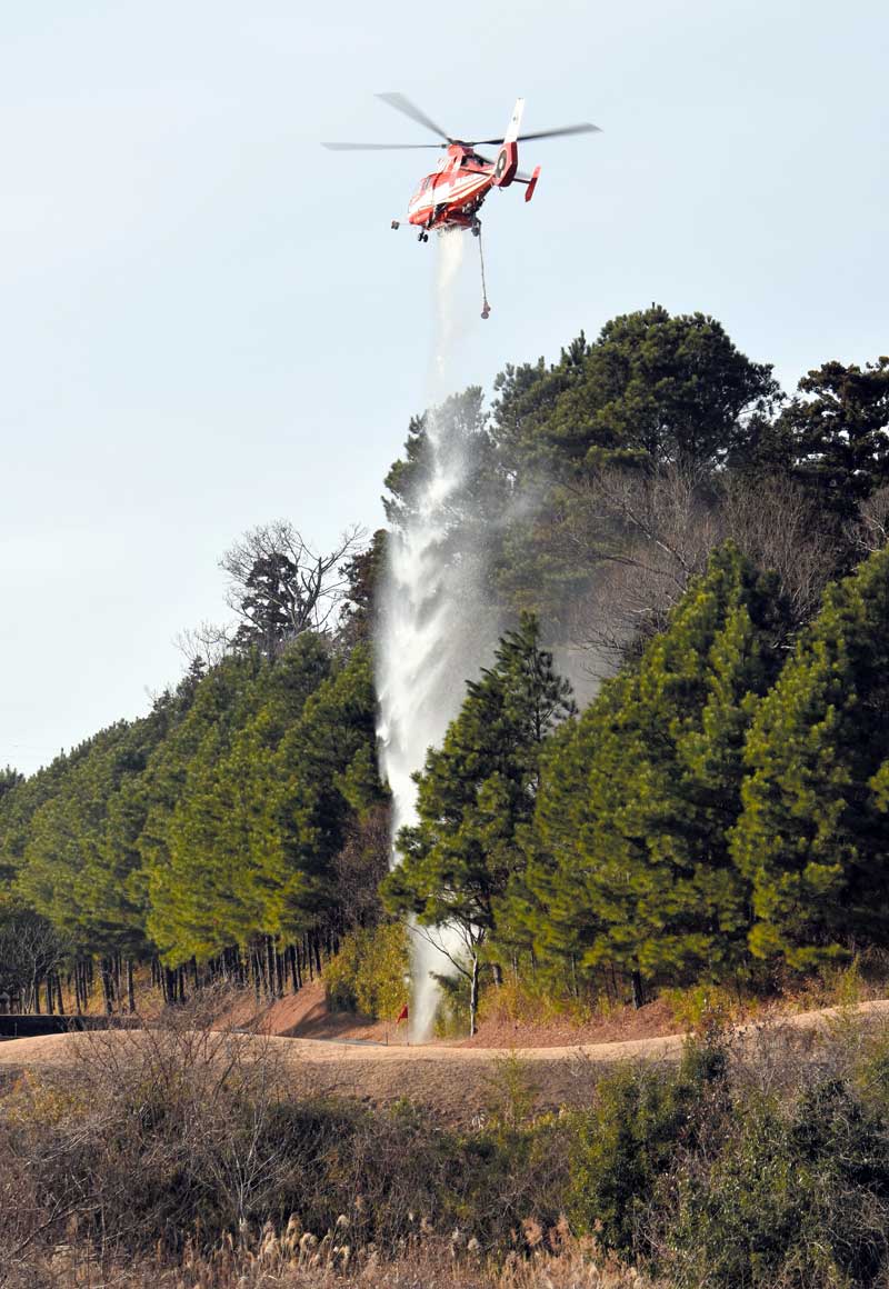 空中から消火活動を行う千葉市消防局のヘリコプター＝６日午後２時５５分ごろ、千葉市若葉区