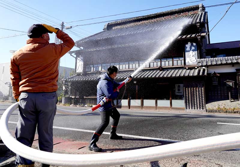 古くからの木造建物の屋根に水をかける新丁区の住民＝１０日、大多喜町