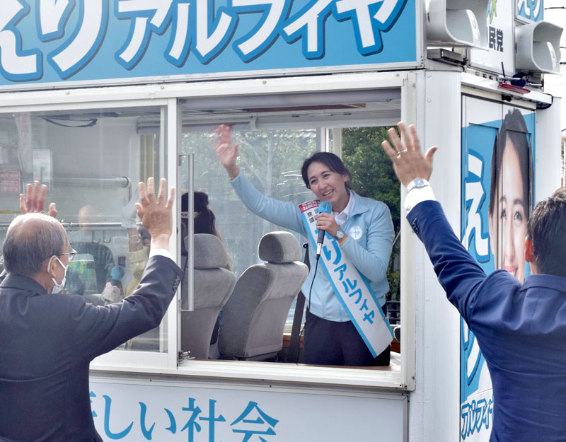 ガラス張りの選挙カーに乗り、手を振る英利氏＝１４日、市川市