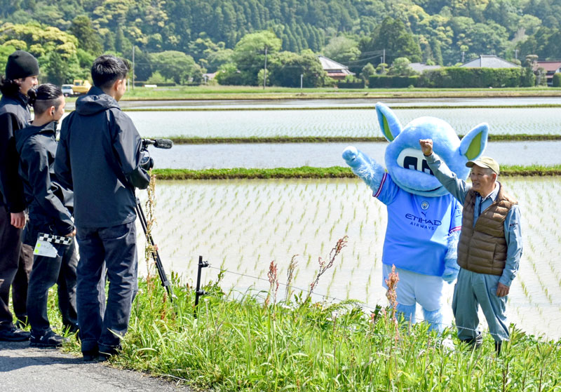 田んぼで動画撮影をするムーンチェスターと藤平社長＝いすみ市