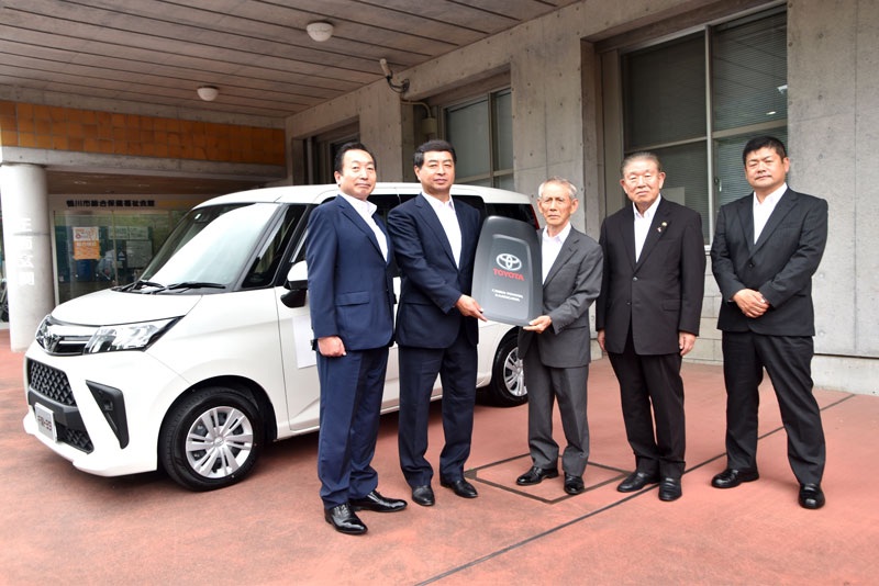 福祉車両の前でレプリカキーを榎本会長（中央）に手渡す月城副理事長（左から２人目）＝鴨川市