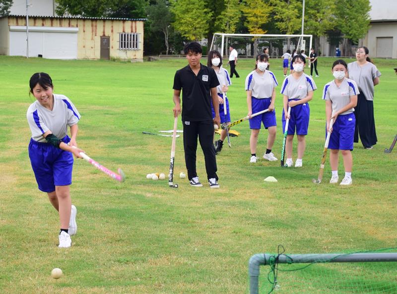 大原高校のホッケー部員（中央）が見守る中、シュートを放つ中学生＝２２日、白子町立白子中