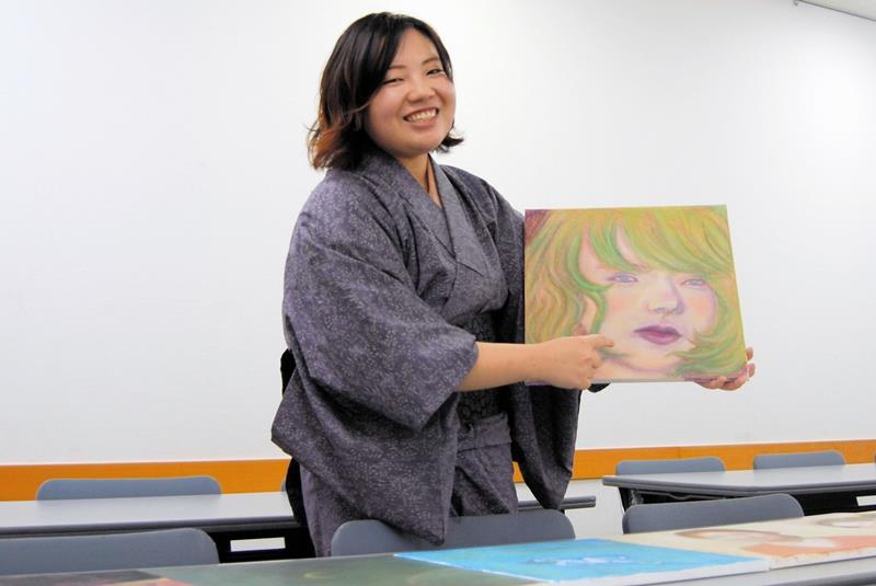 自作の絵を説明する大田垣さん。目や唇にこだわったという＝千葉市緑区