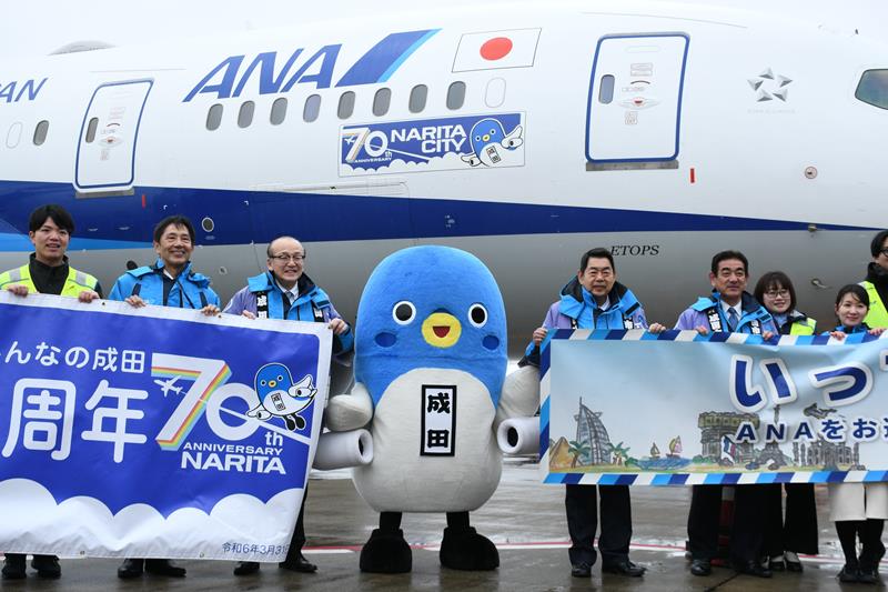 自分のイラストが入ったロゴマークが貼られた機体を紹介するうなりくん（中央）ら＝２月２３日、成田市の成田空港