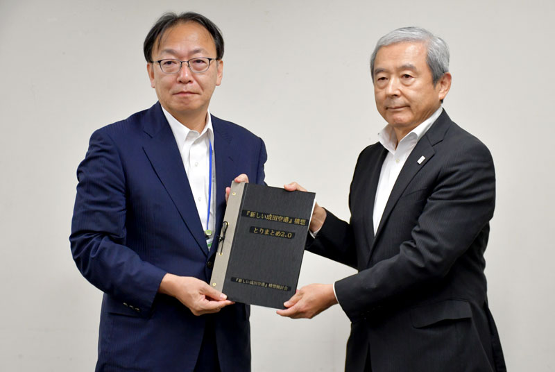 新ターミナル建設などを目指す「『新しい成田空港』構想」の報告書を平岡航空局長(左)に手渡すNAAの田村社長=3日、東京都千代田区の国交省