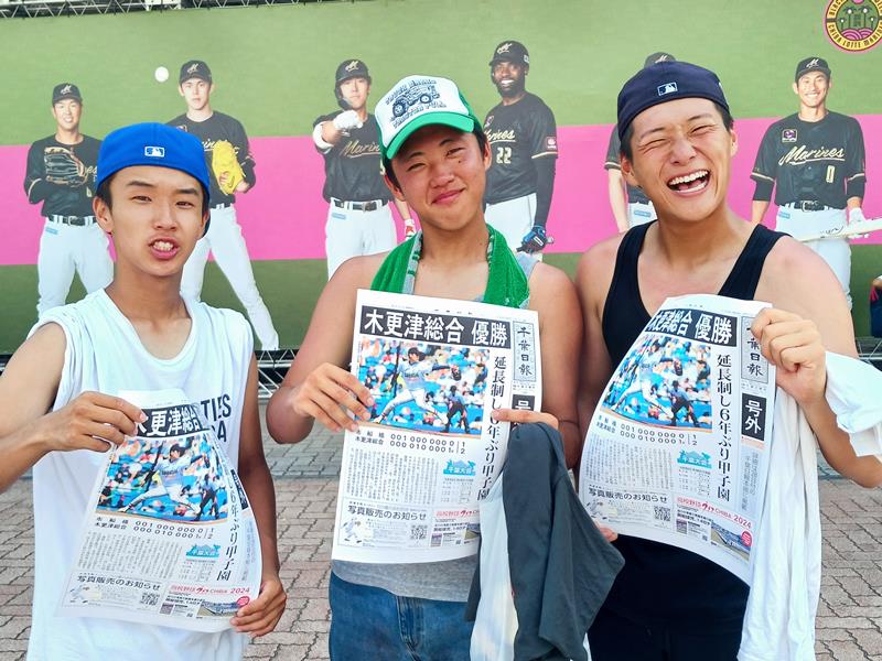 木更津総合の優勝を速報した号外を掲げる高校野球ファンの観客＝２７日、ＺＯＺＯマリンスタジアム前