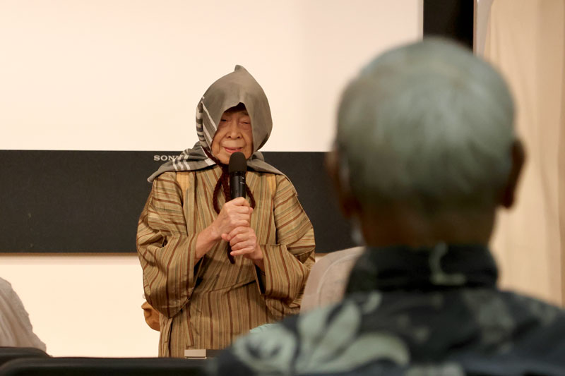 手作りの防災頭巾を被って自身の戦争体験を伝える大野さん=8月8日、千葉市中央区の千葉県庁