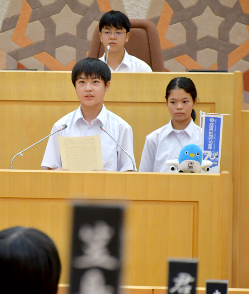 議会の壇上に立って成田市の課題に関する質問をする中学生ら＝成田市
