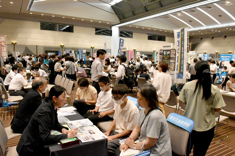 学校のブースで受験相談などをする来場者ら＝１６日、千葉市美浜区