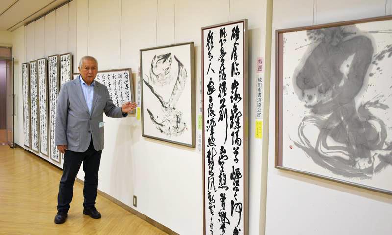 成田市書道協会展の受賞作品を紹介する山口会長＝同市