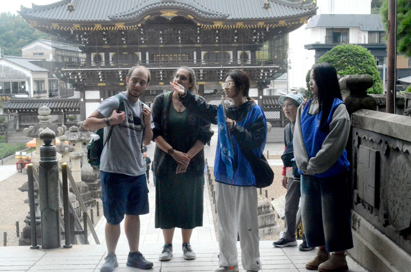 成田山新勝寺を訪れた外国人観光客に英語で案内活動を行う城西国際大観光学部の学生（左から３人目）＝１日、成田市