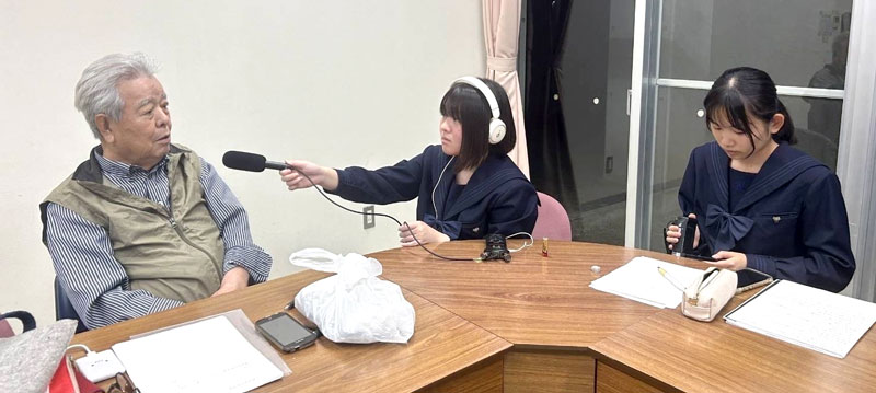 福田村事件追悼慰霊碑保存会代表の市川さん(左)を取材する柏南高放送部の生徒たち(同校放送部提供)