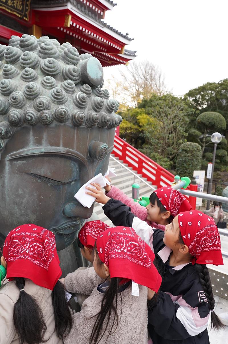 さらし布で大仏の顔を拭く園児たち