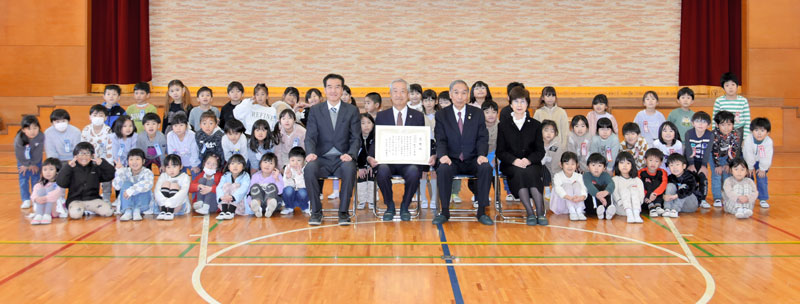 ３小中学校に滑り台などを寄贈した飯沼会長（中央左）と、感謝状を手渡した小坂町長（同右）ら＝１９日、酒々井小