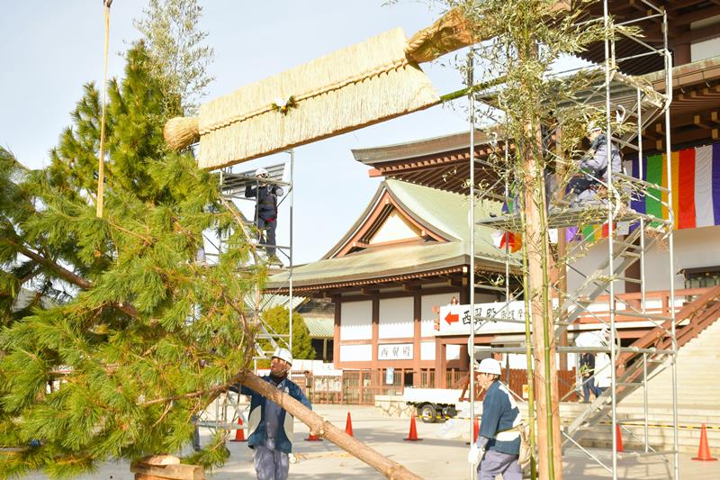 成田山新勝寺の大本堂前に来年の初詣客を迎える大しめ縄と門松を飾り付ける工務係員＝２５日、成田市