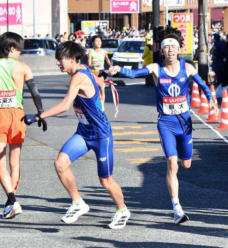 順大３区の海老沢憲伸（左）にたすきを渡す２区の玉目陸＝横浜市戸塚区