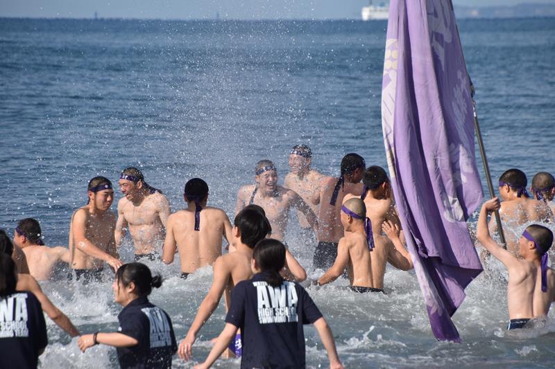 水しぶきを上げながら海に入る安房高生ら