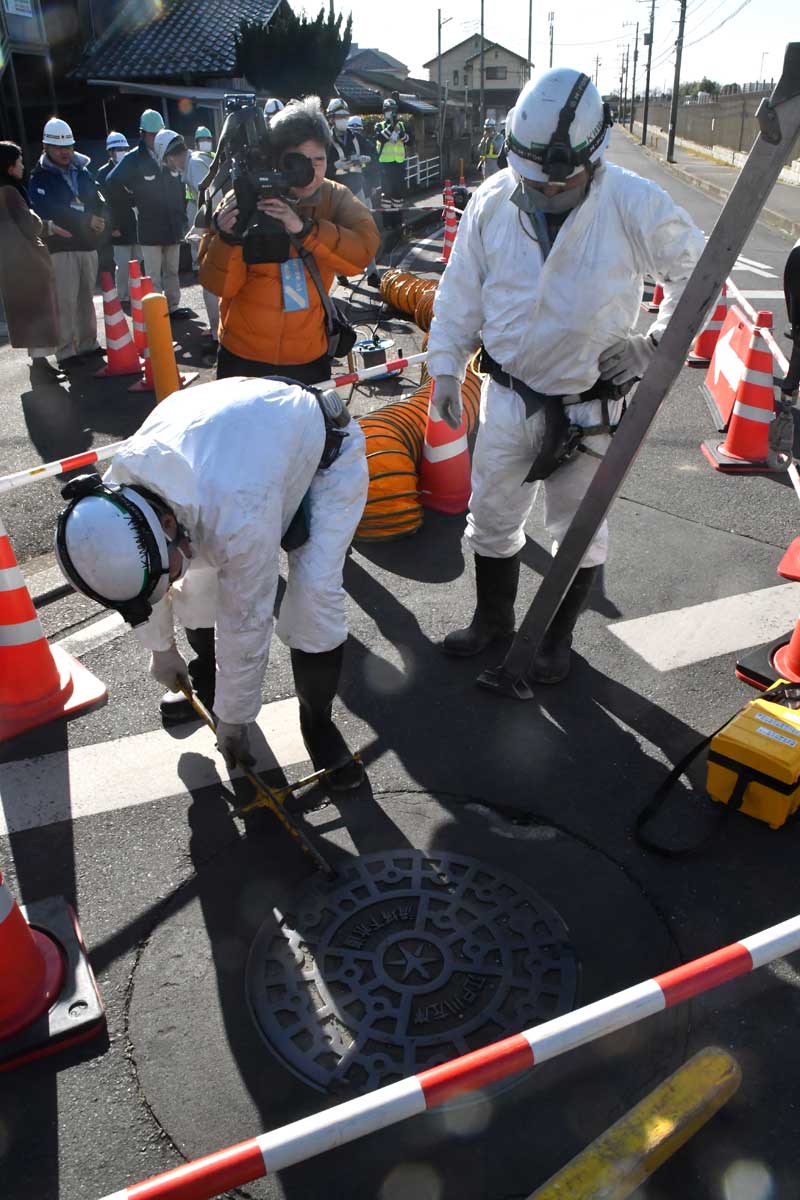 マンホールのふたを開け、点検を開始する作業員＝３１日午後、松戸市栗山