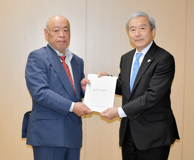 NAAの田村社長(右)に「私たちの思い」を手渡す石井会長=成田市