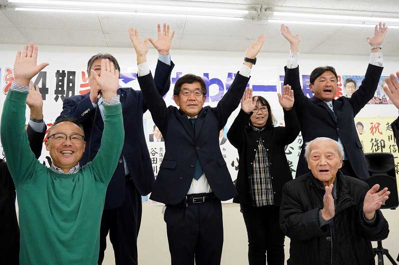 ４回目の当選が決まり、事務所で支援者らと万歳する越川氏（中央）＝２７日深夜、銚子市
