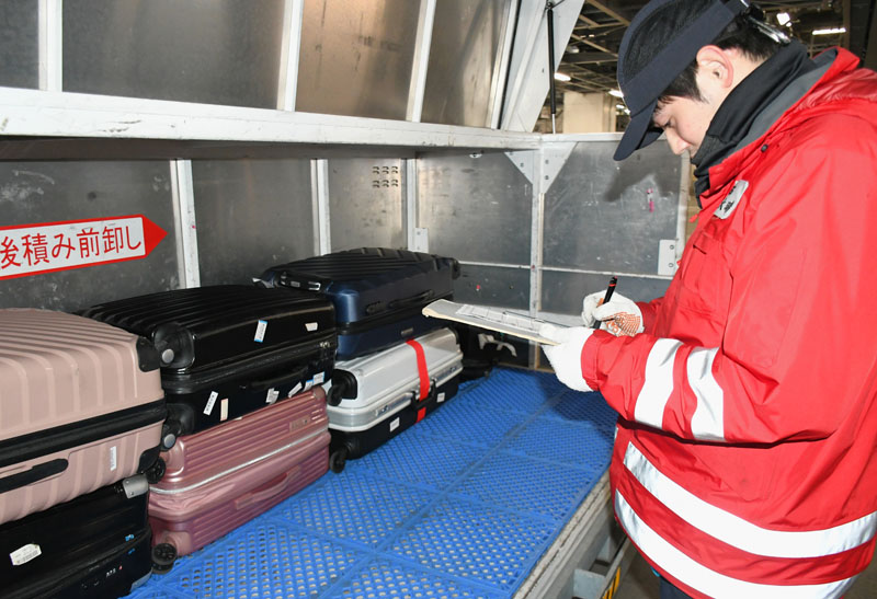 手荷物を正しい送り先に届けるため確認作業をする谷奥さん＝成田市