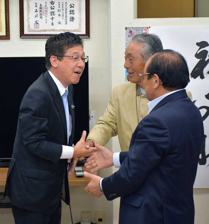 事務所に駆け付けた支持者らと握手をして当選を喜ぶ自民党の松本氏（左）＝２７日、印西市