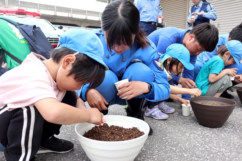 植木鉢に朝顔の種をまく園児と隊員ら