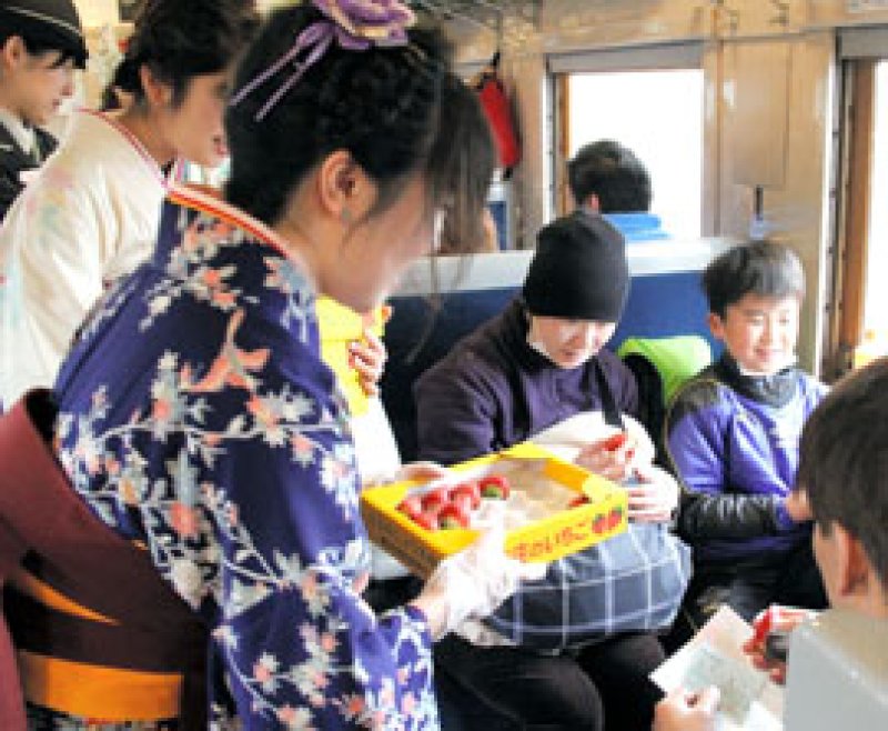 デゴイチの車内で乗客に東庄町名産のイチゴ「アイベリー」を配る女性職員＝３０日
