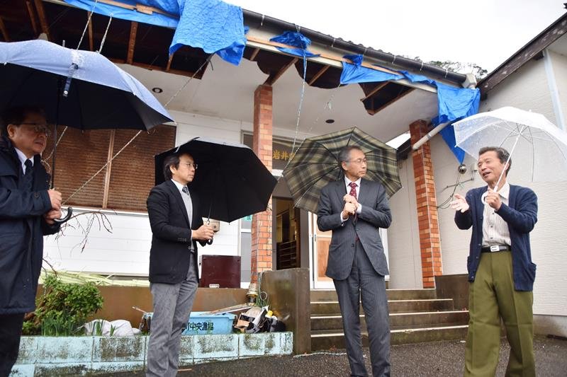 台風の爪痕が残る中、漁協職員（右）から被害状況の説明を受ける検証会議委員＝２２日午後３時１０分ごろ、南房総市富浦町多田良の富浦漁港