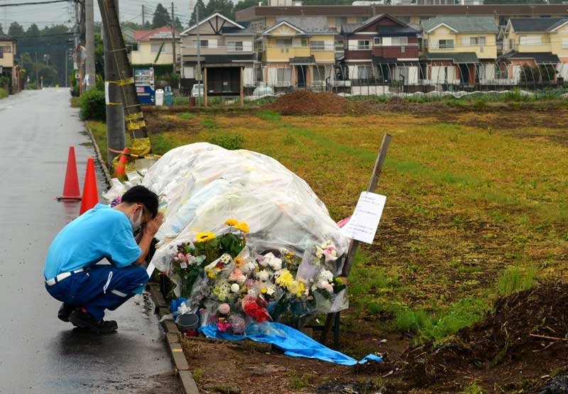 事故現場に設けられた献花台で手を合わせる男性＝５日午後、八街市