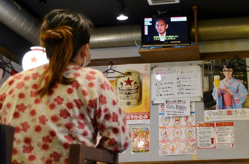 菅首相辞意のニュースを見る飲食店の店長＝３日午後、千葉市中央区