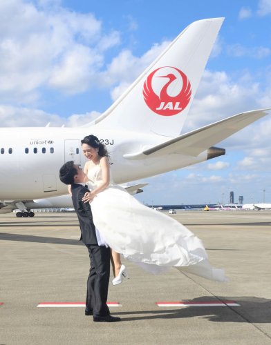旅客機の前で撮影に臨む角田敬さんとゆうかさん＝１１日、成田空港