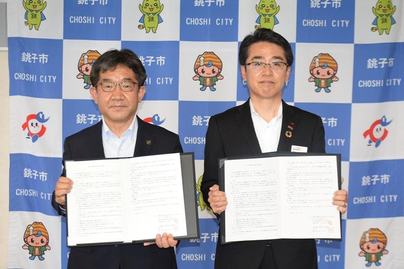 協定書を手にする越川信一市長（左）と古賀計久支社長＝９日、銚子市役所
