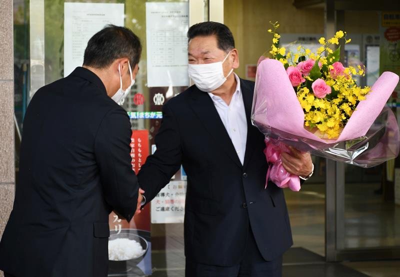新たに町長に就任する橋本氏（左）から花束を受け取った岡田町長＝２０日、栄町役場
