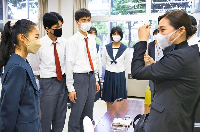 成田国際高校の生徒に客室乗務員の業務を紹介する卒業生の成本さん（右）＝成田市
