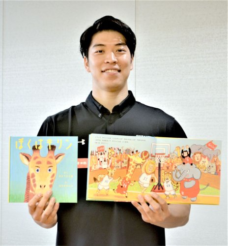 完成した絵本「ぼくはキリン」を披露する佐藤選手＝８日、船橋市役所