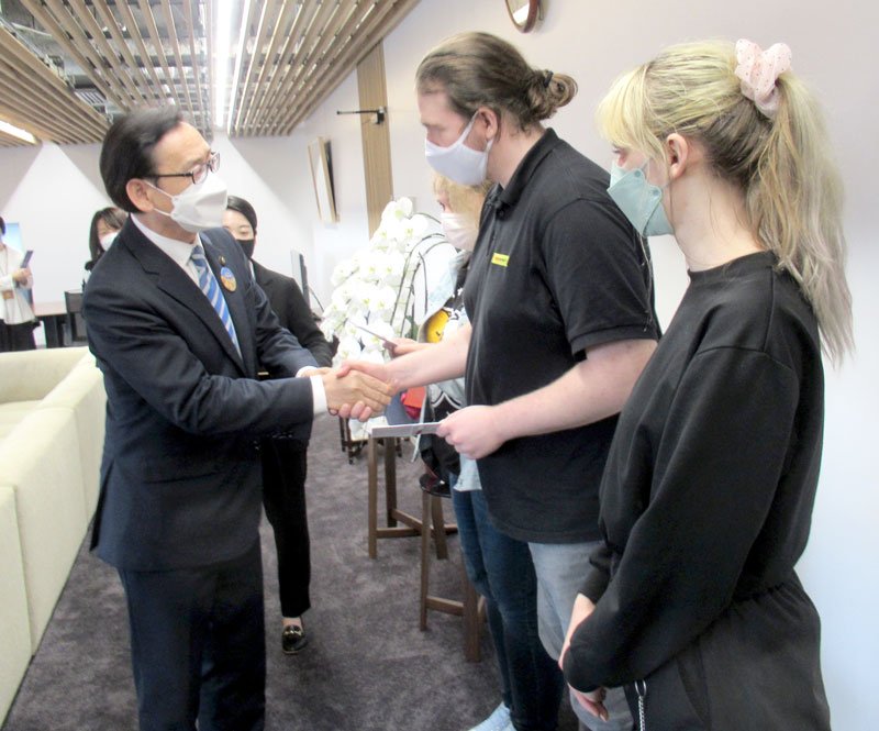 田中市長（左）から見舞金を受け取る、ウクライナから避難してきた人たち＝８日、市川市役所