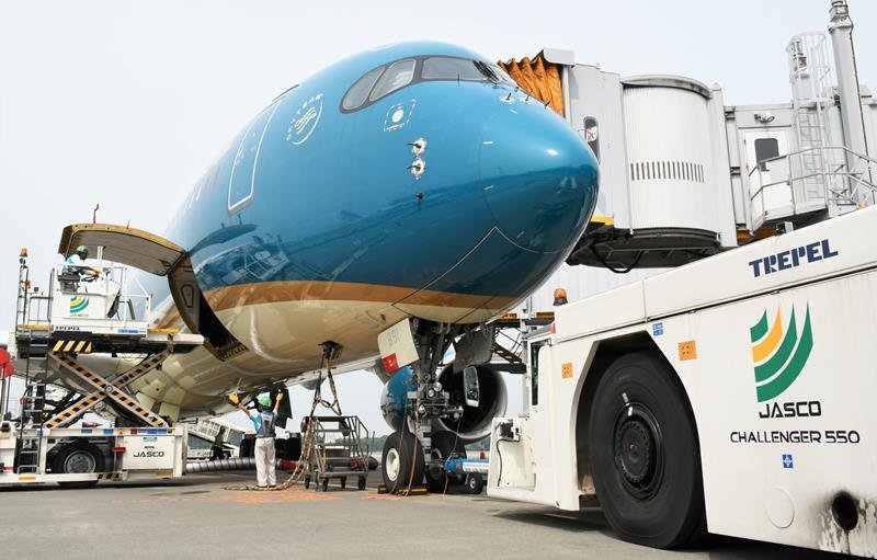 離陸に向けて日本空港サービスの社員が搭載作業やプッシュバックの準備を進めるベトナム航空の機体＝６月２１日、成田空港
