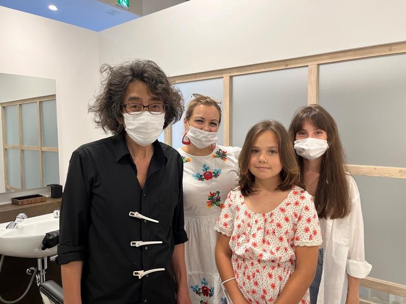 ヘアカット後、笑顔を見せる少女（右から２人目）とその家族ら、同店スタッフ（左）
