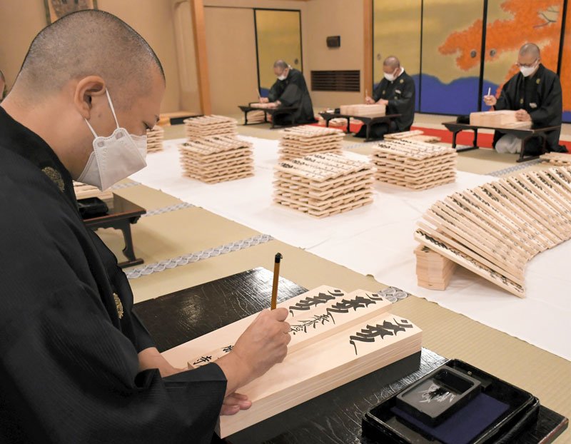 成田山新勝寺で来年の正月に向けた護摩札作りが始まり、一字一字に願いを込めて筆を入れる僧侶＝１５日、成田市