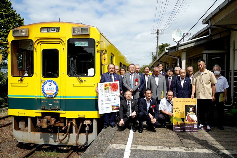 記念ヘッドマークが掲示された列車と写真に収まる関係者＝１５日、大多喜駅