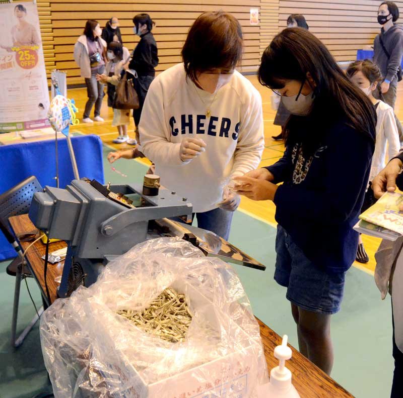 地元の水産加工品会社のブースで煮干しのパック詰めを体験する児童＝大網白里市