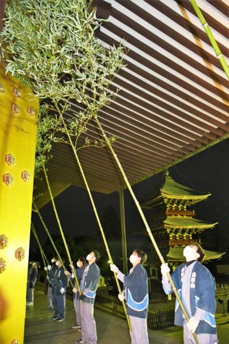 大本堂の正面軒下をササ竹で払う成田山新勝寺の職員＝１３日午前５時５５分ごろ、成田市