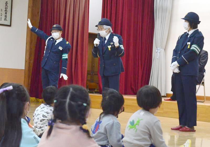 「道路を渡る時は手を上げる」などの約束事を園児に教える東金交通安全協会員ら＝９日、東金市
