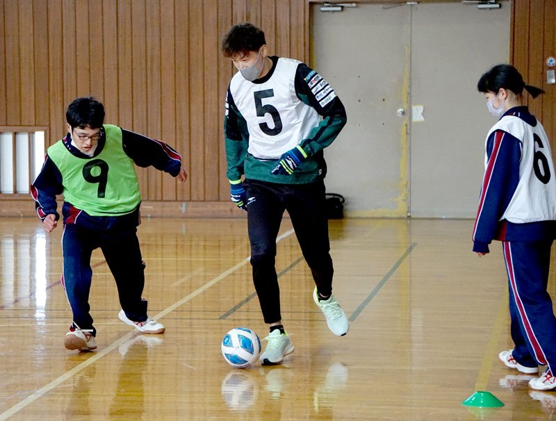ＶＯＮＤＳ市原ＦＣの選手（中央）とプレーを楽しむ生徒＝市原市の県立市原特別支援学校つるまい風の丘分校
