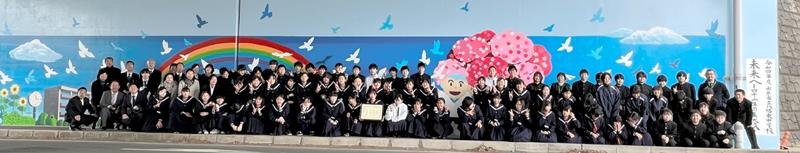 完成した巨大壁画の前で記念写真に納まる八幡東中学校の生徒＝市原市の館山自動車道高架下トンネル
