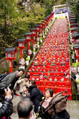 遠見岬神社の石段６０段に飾られたひな人形約１８００体の前で写真を撮る親子連れら＝２月２４日、勝浦市