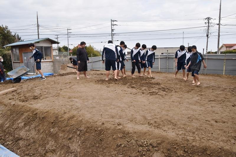 土俵の基礎となる土をはだしで踏み固める生徒たち＝館山市
